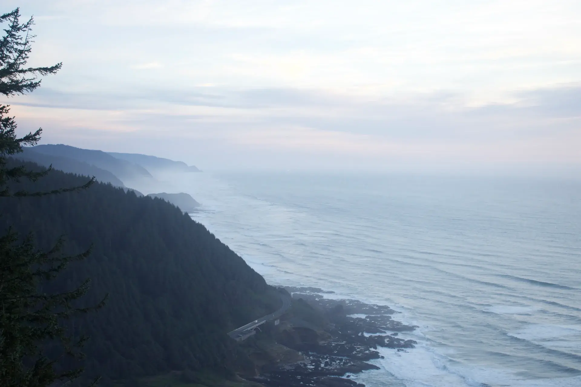 A coastal highway beneath forested cliffs