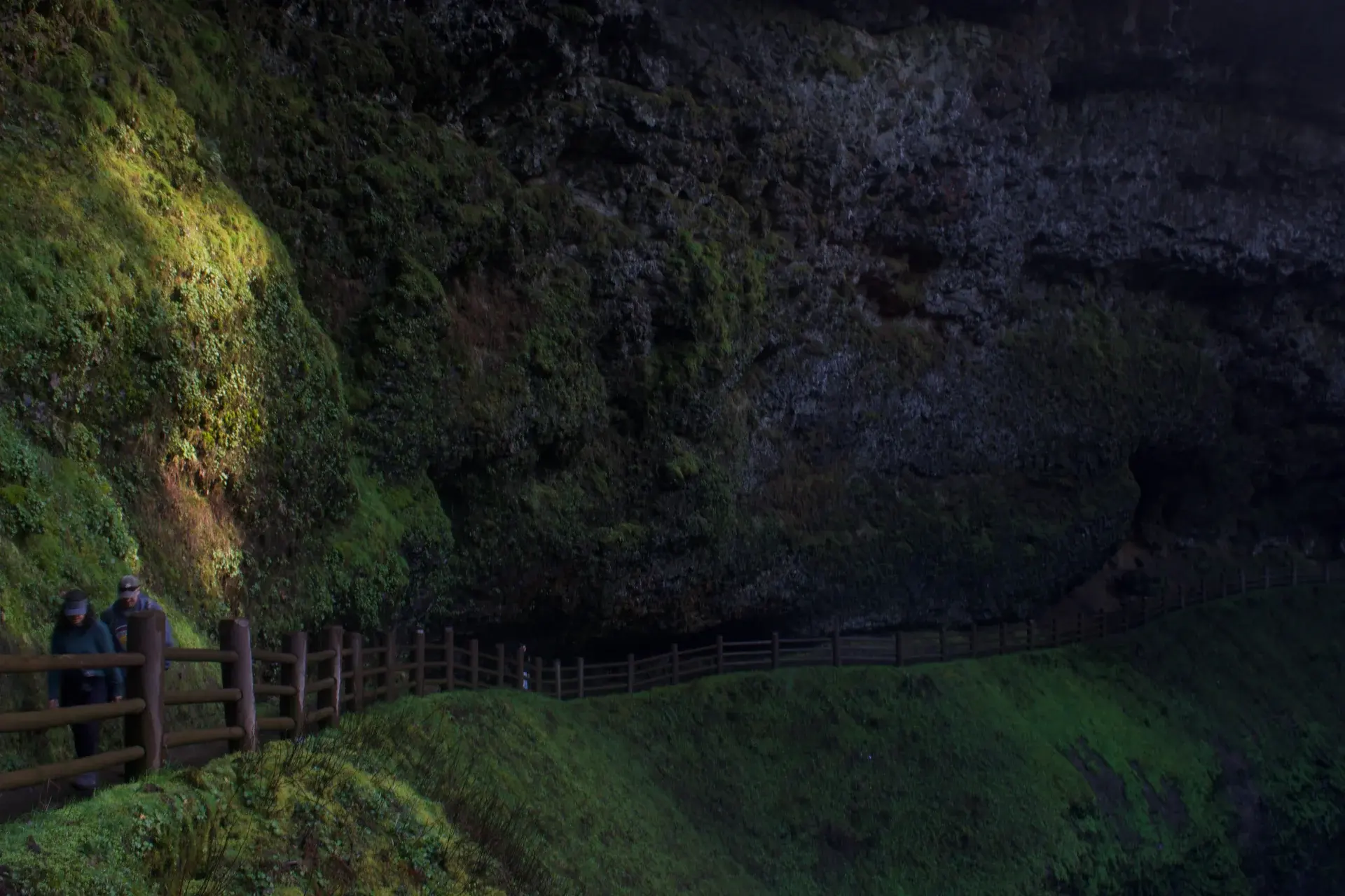 Hikers on a path beneath a rocky overhang